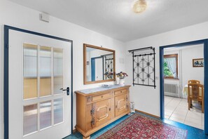 A hallway with a wooden cabinet, a mirror, and a patterned rug.