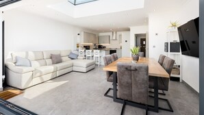 A modern living space with a dining area, a sofa, and a kitchen in the background. - Executive Harborne House (Harborne)