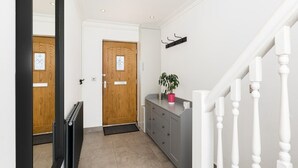 A hallway with a wooden door, a radiator, a grey cabinet, and a white staircase. - Executive Harborne House (Harborne)