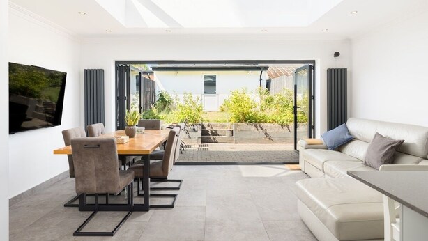 A modern living room with a dining area, a sofa, and a TV mounted on the wall. - Executive Harborne House (Harborne)