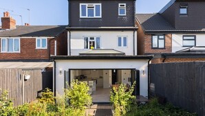 A modern two-story house with a visible kitchen and dining area, a fenced backyard, and a wooden fence. - Executive Harborne House (Harborne)