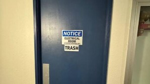 A blue door with a notice sign indicating an electrical room and a trash bin.