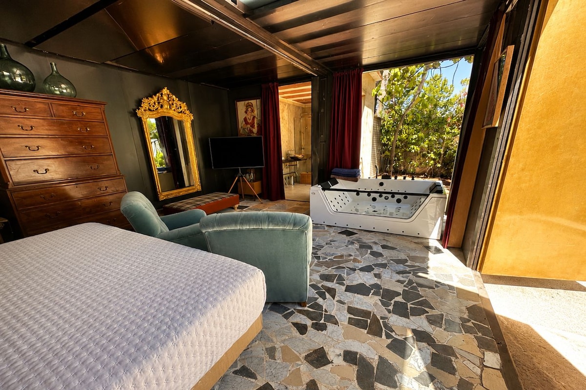 Ein Schlafzimmer mit Bett, Sofa, Fernseher, Spiegel und Whirlpool.