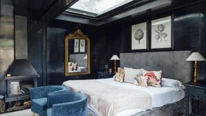 A bedroom with a large bed, a fireplace, and a skylight. - Hotel Boutique Pinar by Bossh Hotels (Jábaga)