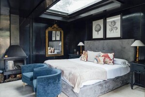 A bedroom with a large bed, a fireplace, and a skylight.