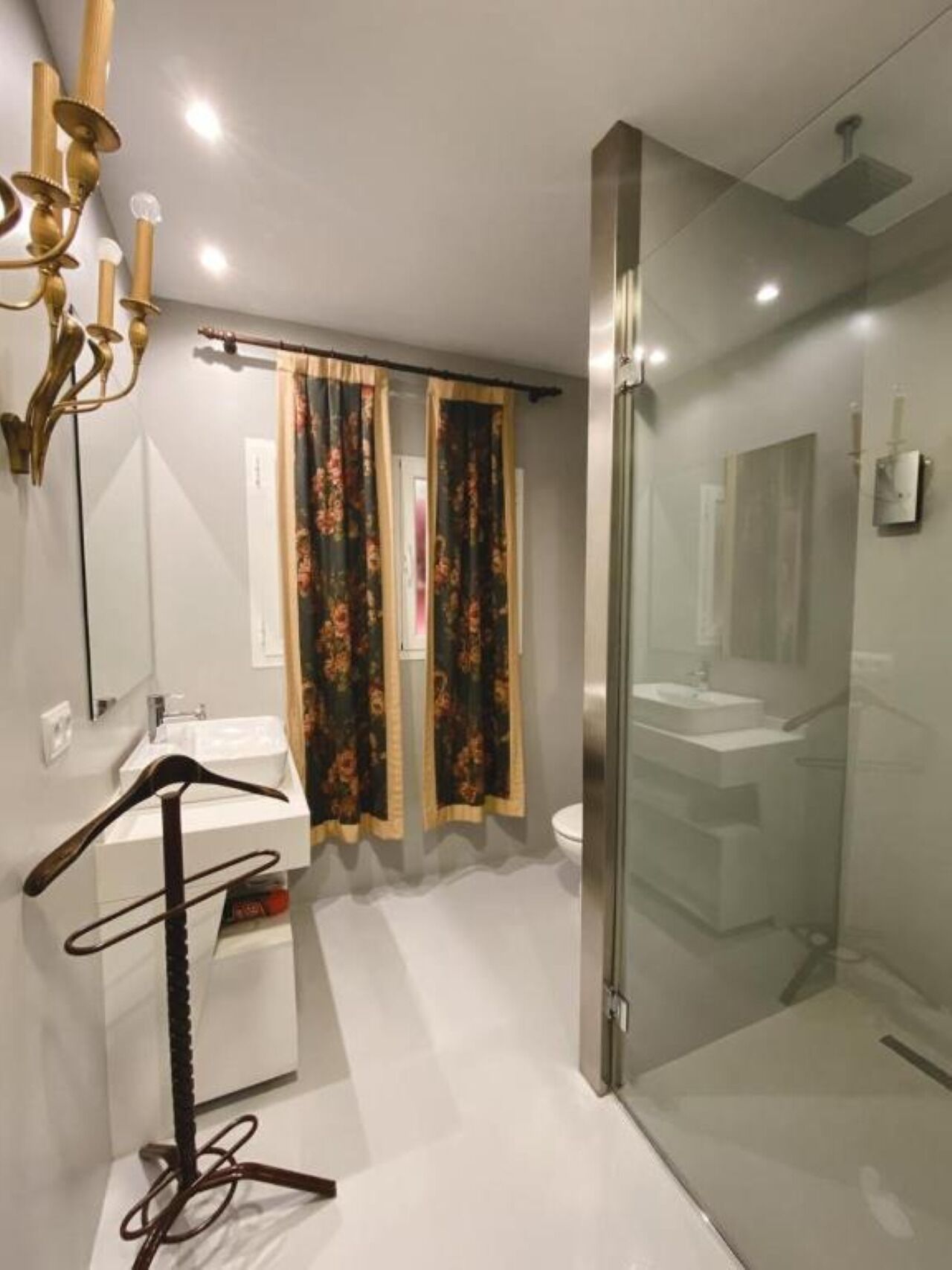 Un baño moderno con cabina de ducha de vidrio, un lavabo blanco y un espejo.