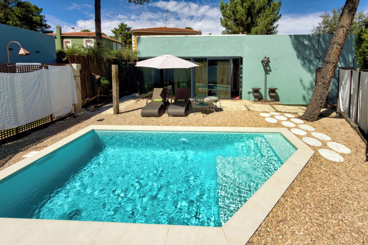 Ein rechteckiger Swimmingpool mit klarem, blauem Wasser, umgeben von Kiesgrund und einer Terrasse mit Stühlen und Tisch.