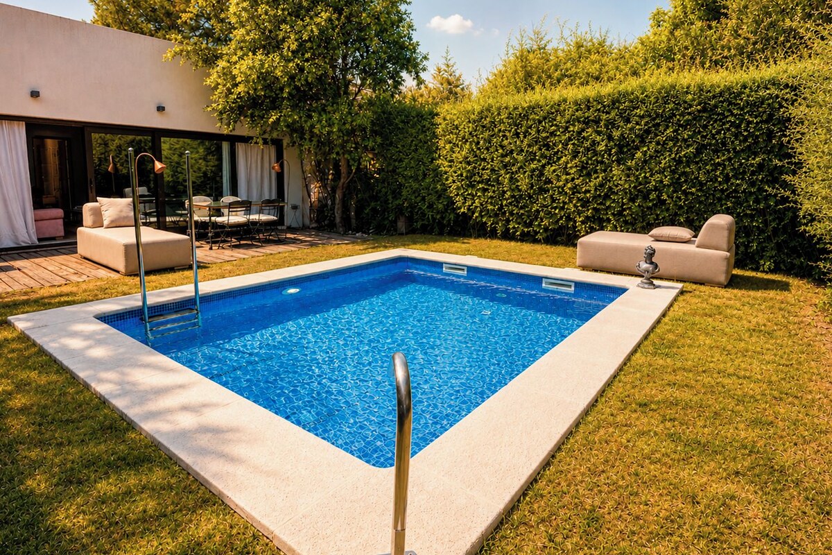 Ein rechteckiger Pool mit Metallleiter, umgeben von einer Rasenfläche und einem Heckenstreifen.