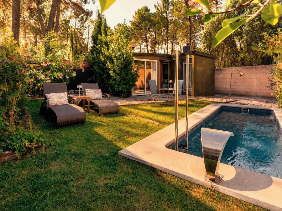 A backyard with a swimming pool, lounge chairs, and a small covered area.