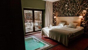 A bedroom with a bed, a small sitting area, and a hot tub. - Hotel Boutique Pinar by Bossh Hotels (Jábaga)