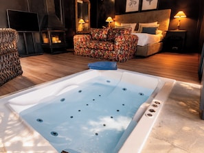 A modern bathroom with a large bathtub, a wicker chair, a sofa, and a bed with a headboard. - Hotel Boutique Pinar by Bossh Hotels (Jábaga)