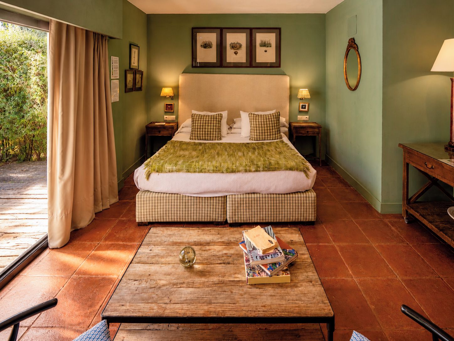 Un dormitorio con cama, mesitas de noche, una mesa de centro de madera y vistas al exterior.