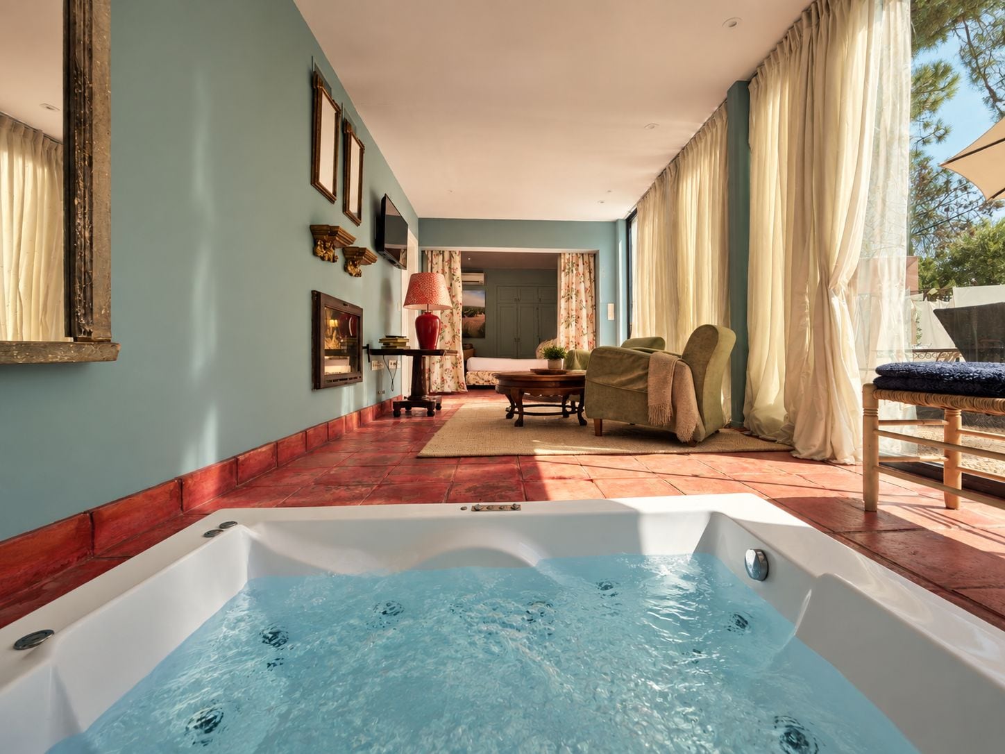 Un área de spa con un jacuzzi, una zona de estar con una mesa y sillas, y vistas al exterior.
