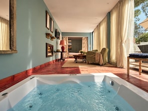 A spa area with a hot tub, a seating area with a table and chairs, and a view of the outdoors.