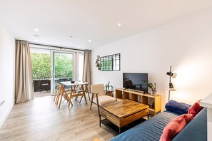 Ein modernes Wohnzimmer mit Fernseher, Sofa, Couchtisch und Essbereich.