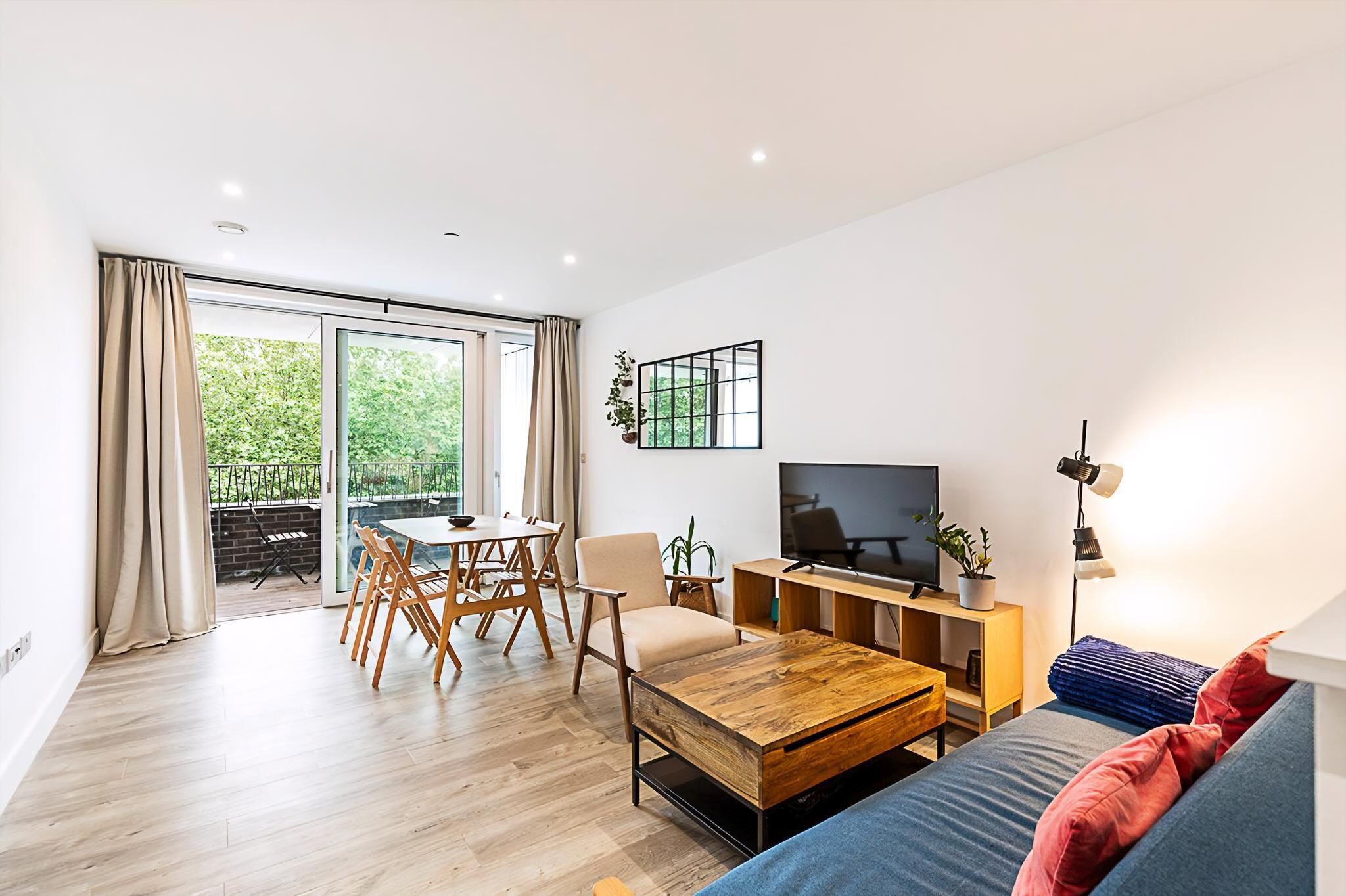 A modern living room with a sofa, coffee table, TV, and dining area with chairs and a table.