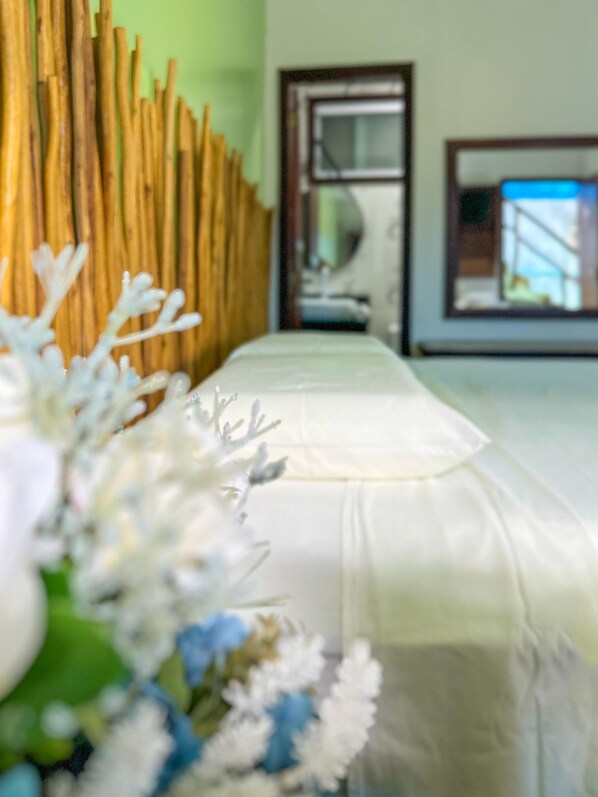 A bed with a white sheet and a wooden headboard. - Pousada Camburi (Cairu)