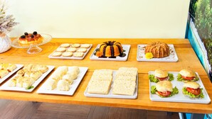 Una mesa con diferentes opciones de comida, incluyendo pasteles, sándwiches y un pastel.