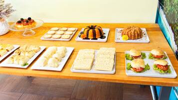 A table with various food items including pastries, sandwiches, and a cake.