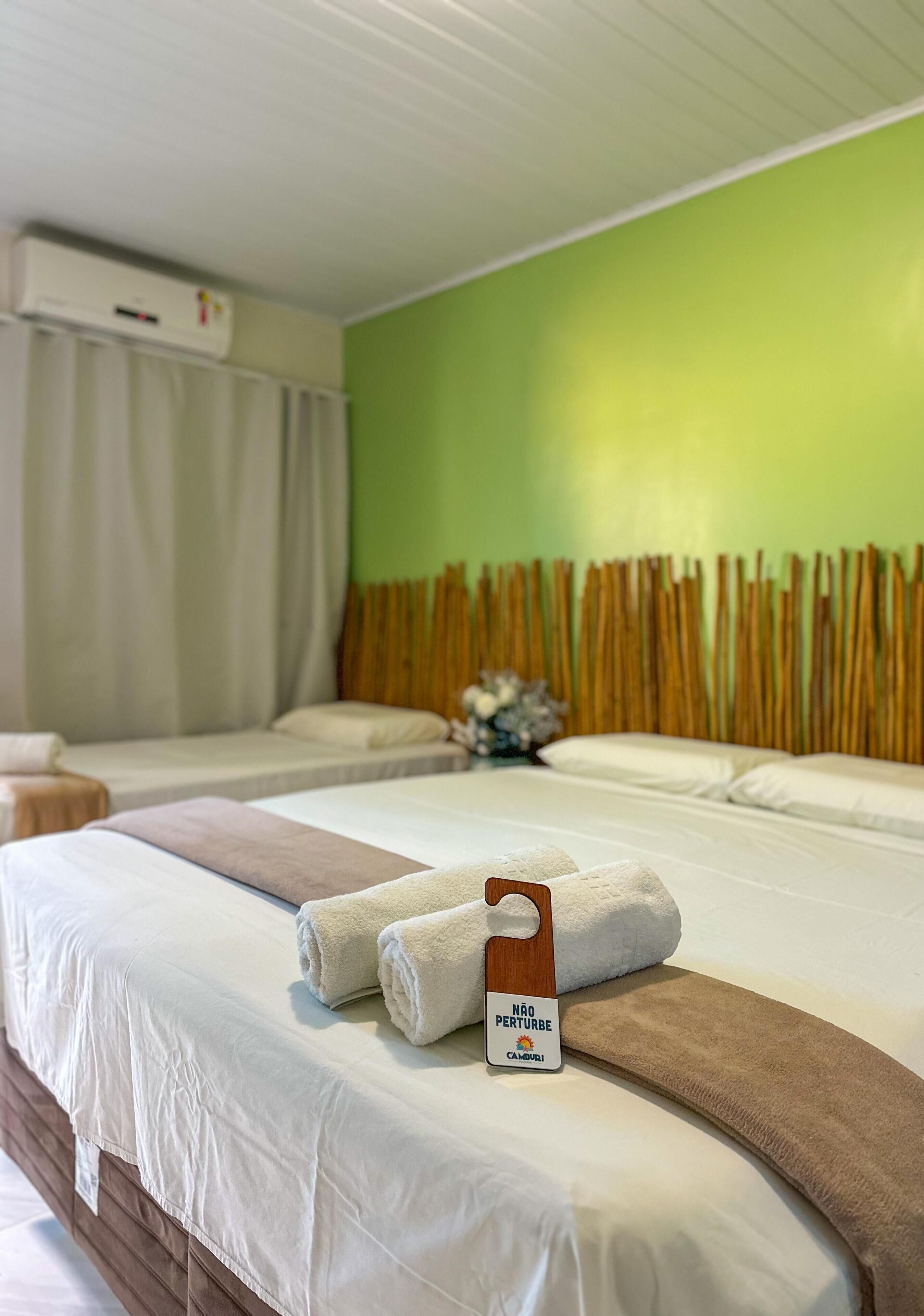 Una habitación de hotel con dos camas, una pared verde y un cabecero de madera.