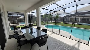 A modern indoor space with a glass enclosure overlooking a swimming pool, featuring a dining table and chairs. - Fantastic Large Pool,Sonoma Resort (Kissimmee)