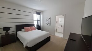 A modern bedroom with a large bed, bedside tables, a TV, and a bathroom visible through an open door. - Fantastic Large Pool,Sonoma Resort (Kissimmee)