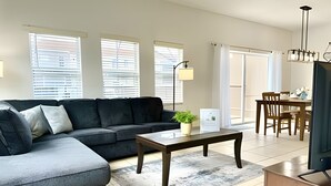 Una sala de estar moderna con un sofá seccional, una mesa de centro y un comedor con una mesa y sillas.