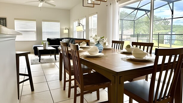 Un comedor con una mesa de madera dispuesta para seis comensales, rodeada de sillas. Amplias ventanas ofrecen luz natural y vistas al exterior con vegetación.