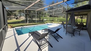 A covered outdoor swimming pool with lounge chairs and a patio area. - New to Market Spacious Private Pool Retreat (Kissimmee)