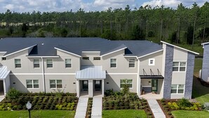 A modern multi-story residential building with a flat roof, large windows, and a well-maintained front yard with a pathway leading to the entrance. - Champions Gate, Pool Home near Disney (Kissimmee)