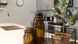 A kitchen with a sink, two brown bottles, a clock, and a plant. - Champions Gate, Pool Home near Disney (Kissimmee)