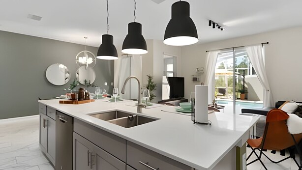 A modern kitchen with a central island, two sinks, and pendant lighting. - Champions Gate, Pool Home near Disney (Kissimmee)