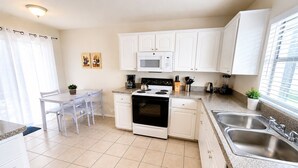 A modern kitchen with white cabinets, a built-in microwave, a stove, and a sink.