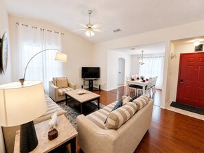 A living room with a sofa, coffee table, TV, and a dining area with a table and chairs.