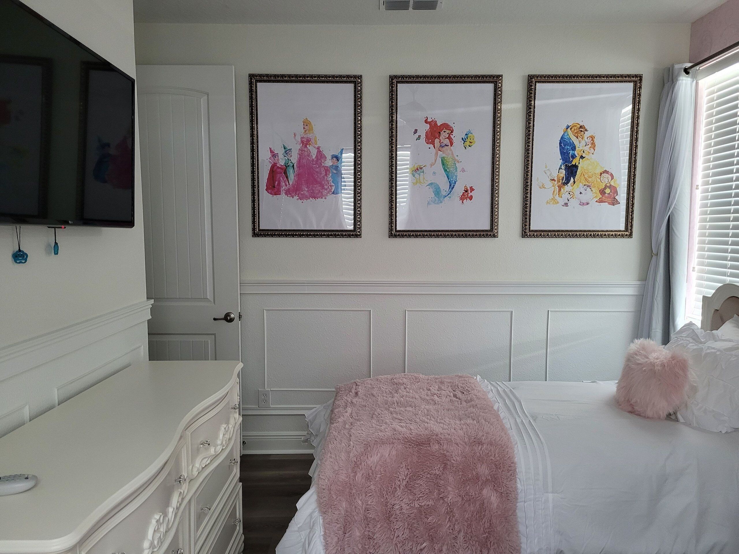 A bedroom with a bed, a dresser, a door, and three framed pictures on the wall.
