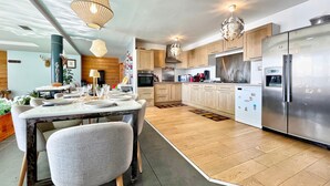 Een moderne keuken met houten kastjes, een roestvrijstalen koelkast en een eethoek met een tafel voor vier personen.