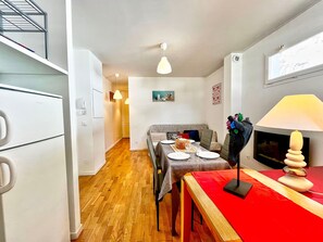 Un espacio habitable compacto con kitchenette, comedor y chimenea.