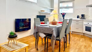 A modern kitchen with white cabinets, a dining area with a table set for two, and a large window providing natural light. - Dream Vacation – Couples, Right by the Slopes (chamrousse)