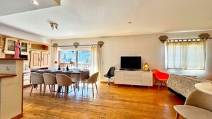 Un vaste espace de vie comprenant une table à manger, des chaises, un téléviseur et un canapé.