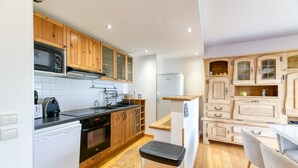 Une cuisine de taille réduite, dotée de meubles de rangement en bois, d’un lave-vaisselle, d’un four à micro-ondes et d’un réfrigérateur.