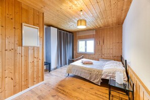 Una stanza con rivestimenti in legno, un letto, una scrivania e una finestra.