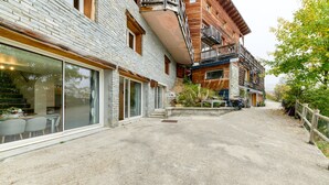 A building with a stone facade, a wooden balcony, and a concrete patio area. - Dream Holiday Apartment - Casserousse - 18 Guests at the Foot of the Slopes (chamrousse)
