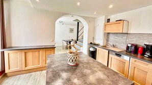 A modern kitchen with wooden cabinets, a central island, and a dining area with a staircase. - Dream Holiday Apartment - Casserousse - 18 Guests at the Foot of the Slopes (chamrousse)