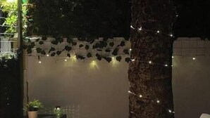 A cozy outdoor seating area with a white sofa, a small table, and string lights. - Mini Paradise Torremolino (Torremolinos)