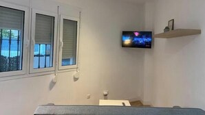 A room with a bed, a TV mounted on the wall, and a window with blinds. - Mini Paradise Torremolino (Torremolinos)