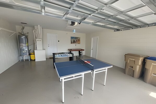 A spacious indoor area with a ping pong table, a water heater, and a painting on the wall.