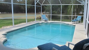 A swimming pool with a covered area, two lounge chairs, and a view of the surrounding landscape. - 10 Minutes to Disney! Pool Home Large Lot (Kissimmee)