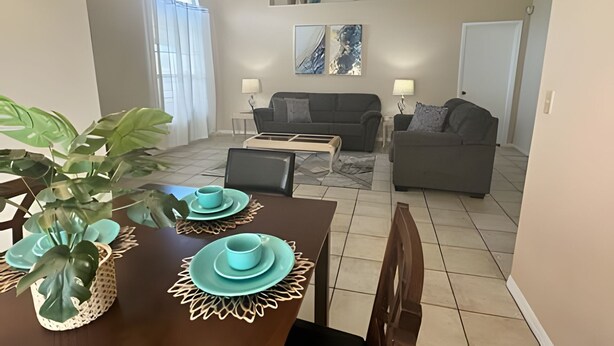 A dining area with a table set for two, a sofa, and a coffee table in a living room. - 10 Minutes to Disney! Pool Home Large Lot (Kissimmee)