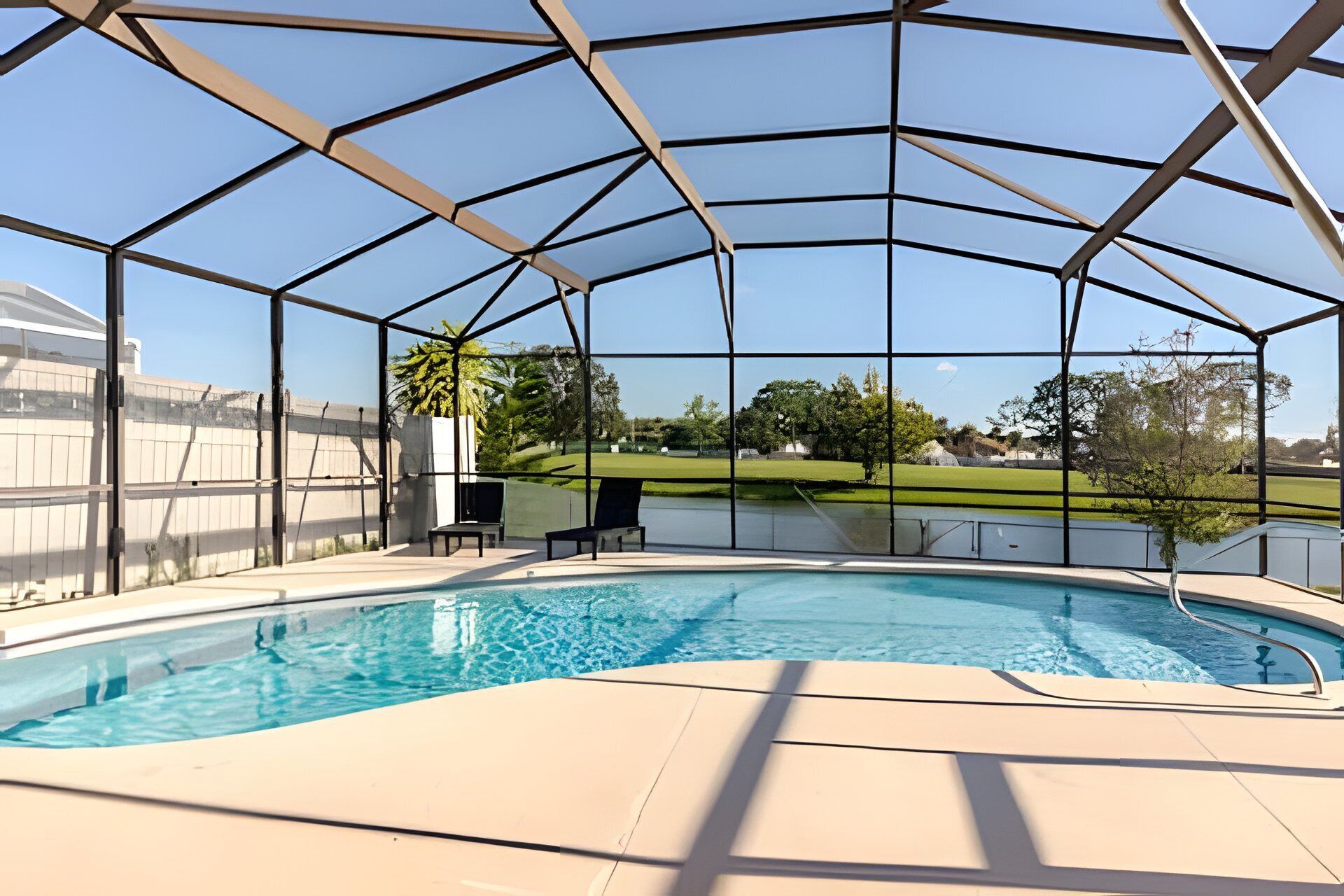 Una piscina amb una vista clara del paisatge circumdant, incloent una zona enjardinada i arbres.