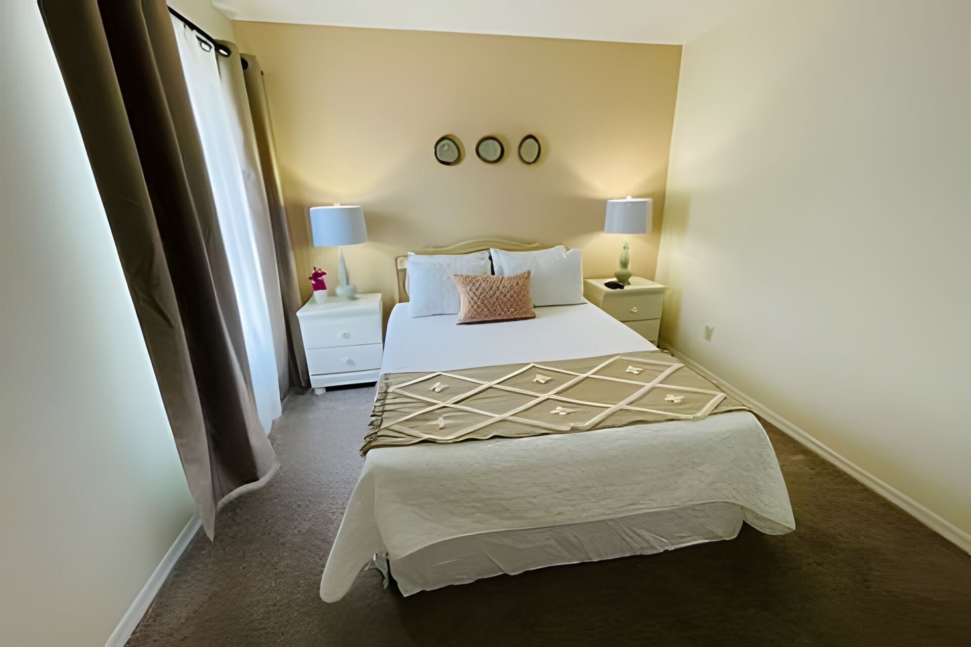 A neatly arranged hotel room with a large bed, two bedside tables, and a wall-mounted clock.